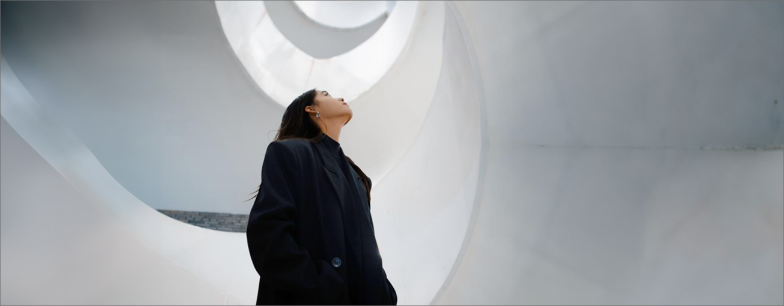 Une femme habillée en noir au centre d'un musée regardant vers le ciel